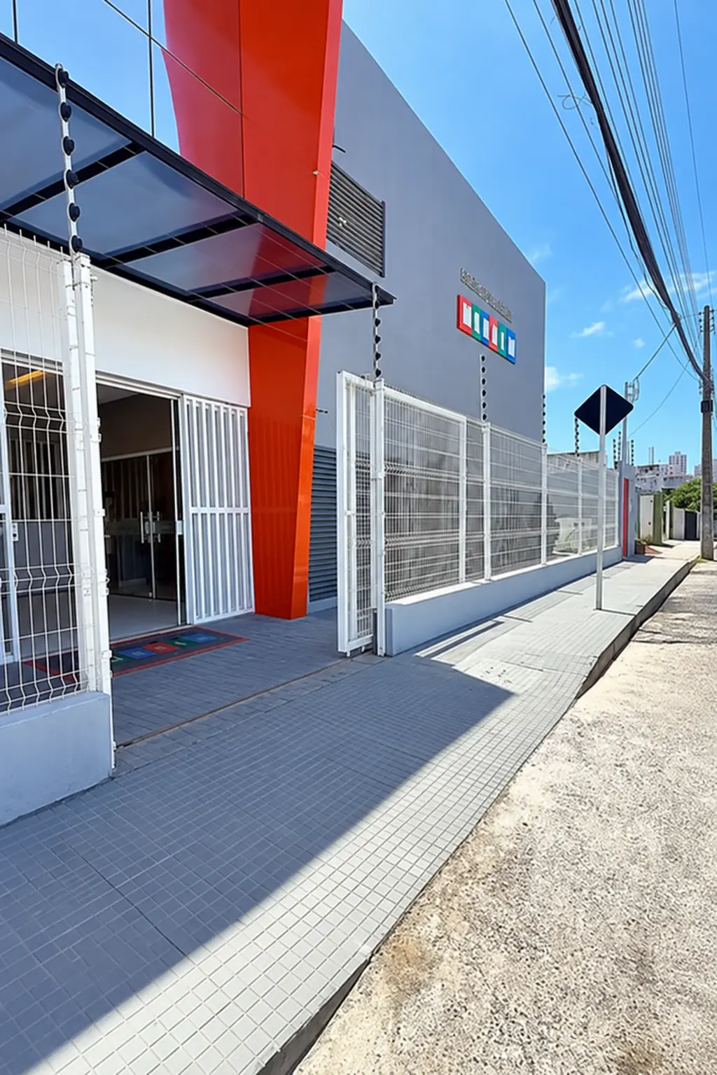 Fachada do Centro Educacional Manaim, com painel laranja e a logo da escola
